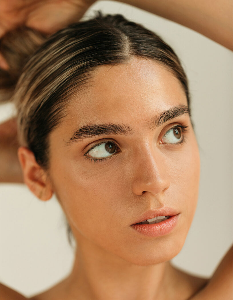 Close-up of a woman with a neutral expression, looking to the side. with thick fluffy brows